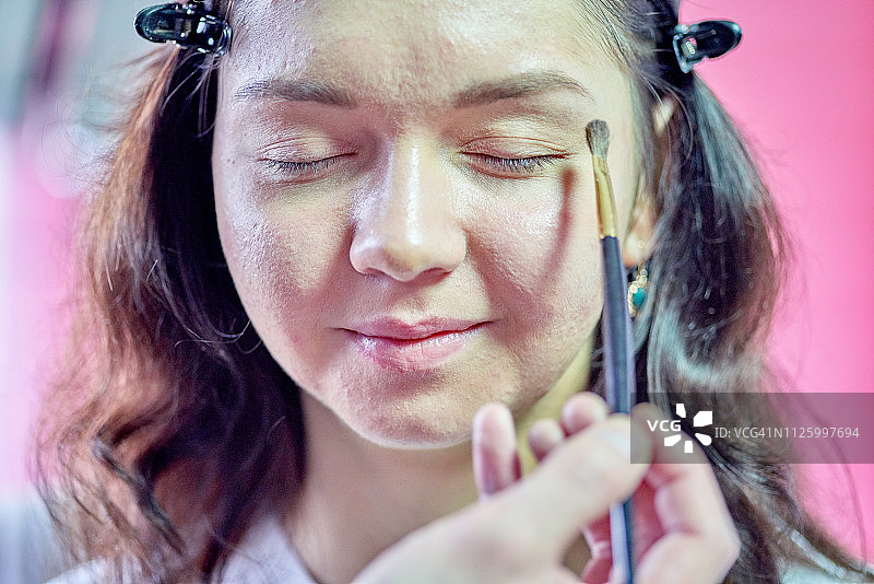 化妆师给年轻女人脸上涂粉底图片素材