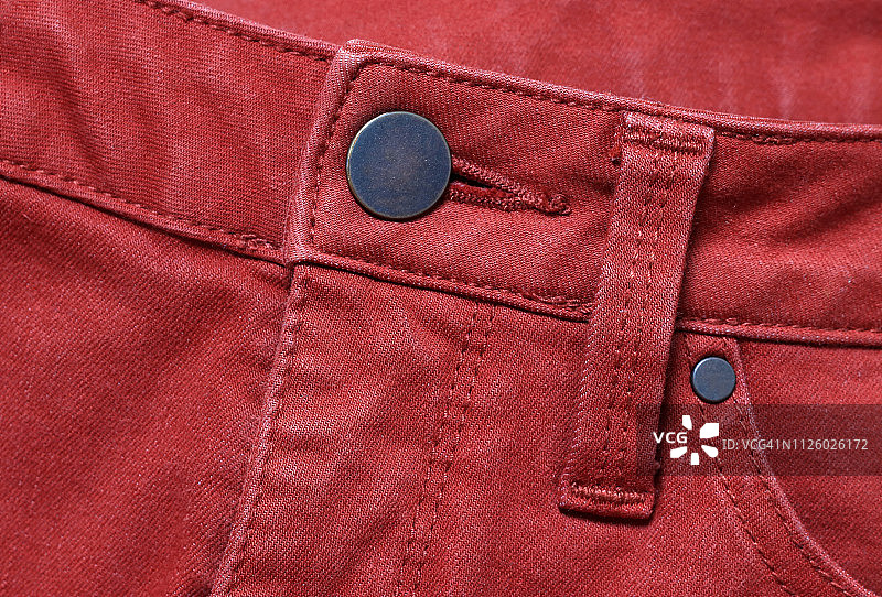 红色牛仔裤，展示前金属纽扣、腰带环和部分前袋图片素材