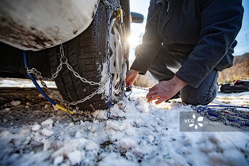 成年男子在汽车上安装轮胎防滑链图片素材