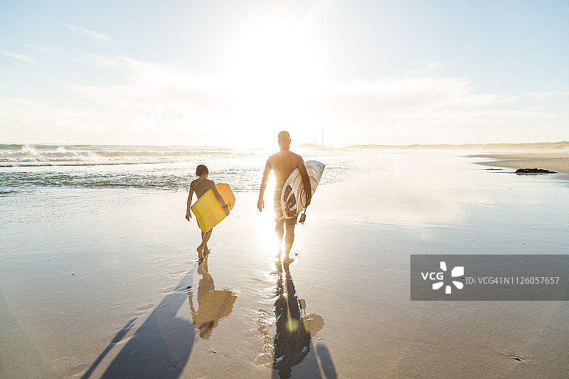 父子在沙滩上一起冲浪图片素材