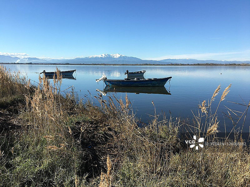 宁静的景色，渔船倒映在水中，背景是山脉图片素材