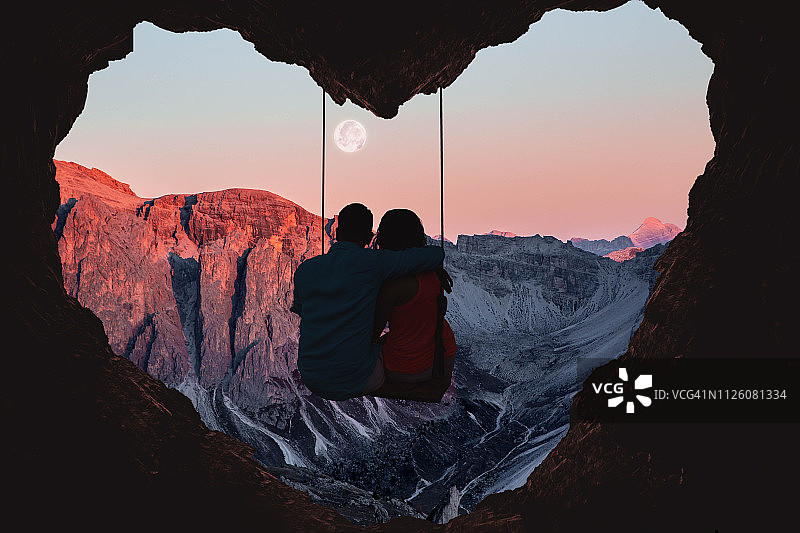 情侣在秋千上欣赏心形山景图片素材