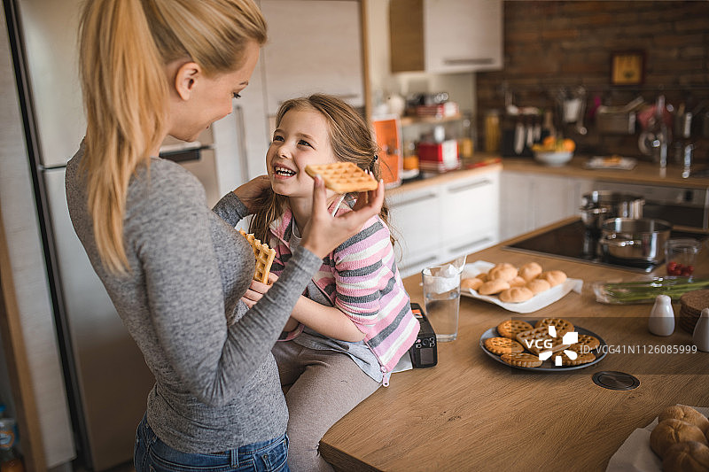 快乐的母亲和女儿在家享用自制华夫饼图片素材
