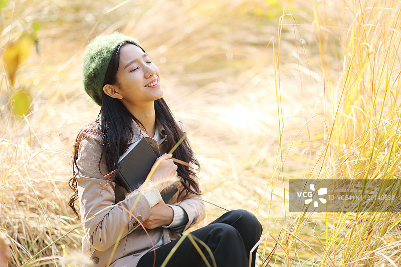 在秋季公园里看书的年轻女子图片素材