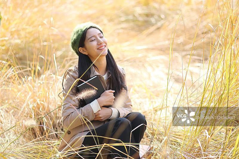 在秋季公园里看书的年轻女子图片素材