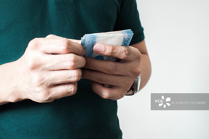 年轻男人在数菲律宾货币图片素材