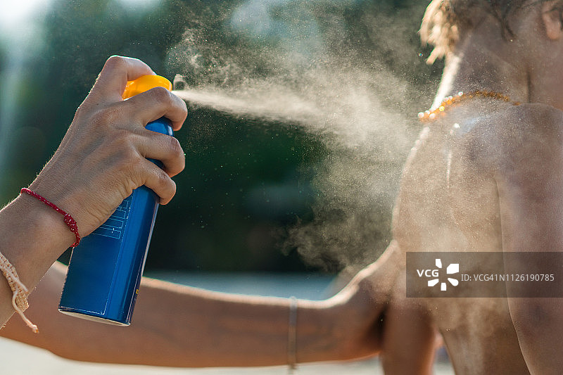 母亲在海滩上为儿子涂抹防晒霜的特写图片素材