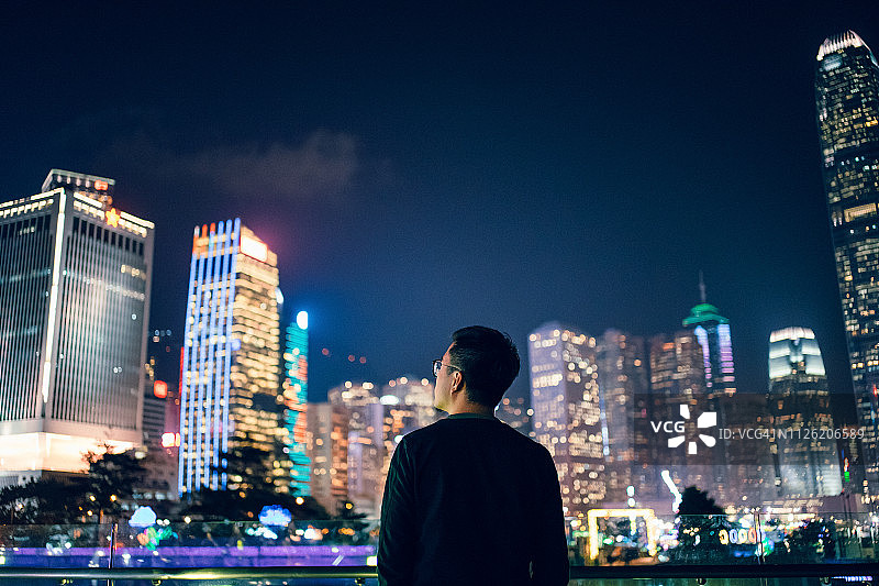年轻男子在香港市中心金融区眺望繁荣景象的背影图片素材