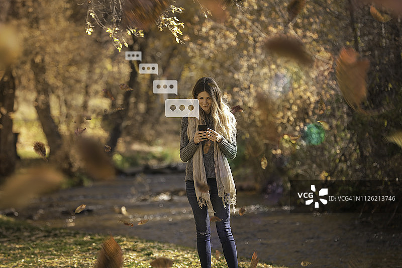 女人在公园里用手机进行秋季散步图片素材