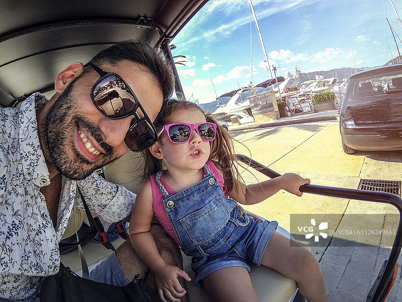 笑脸父亲和可爱的女儿一起开高尔夫球车兜风图片素材
