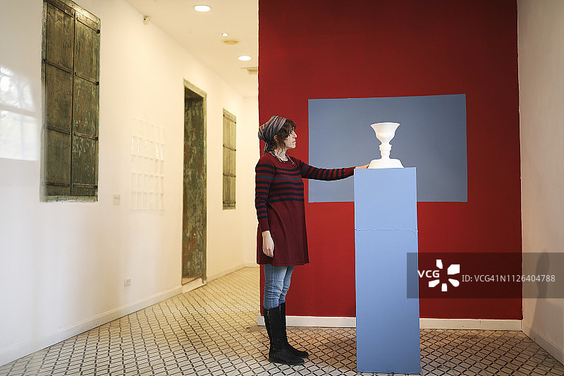 女艺术家在画廊欣赏陶瓷雕塑图片素材