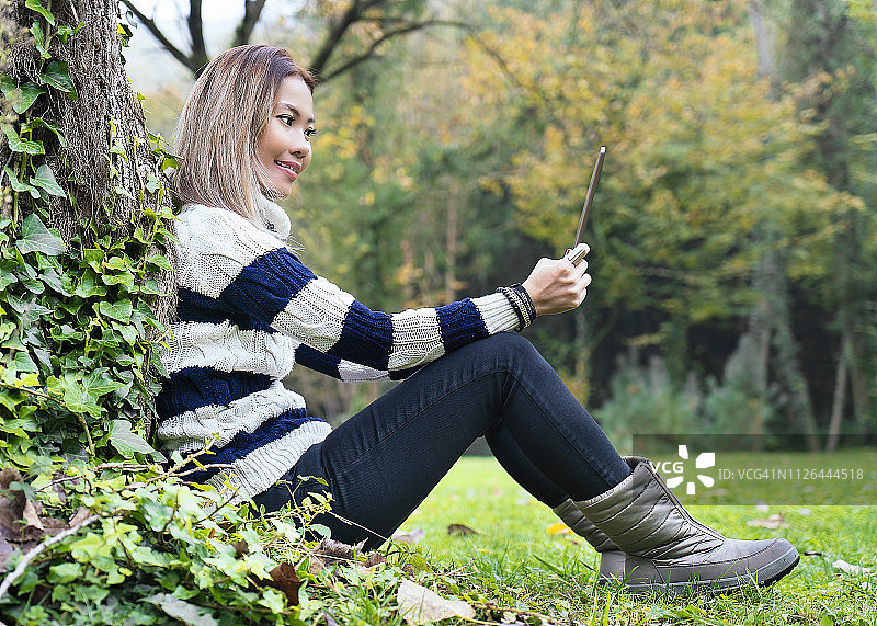 亚洲女性在树林里用平板电脑进行直播聊天图片素材