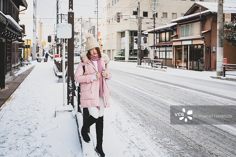 美丽的女人站在日本高山市的雪地路边图片素材