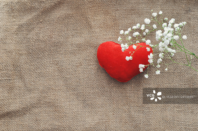 情人节复古乡村爱情卡 - 白色花朵和红色毛绒心形在粗麻布上，特写，顶视图，着色效果，破旧别致风图片素材