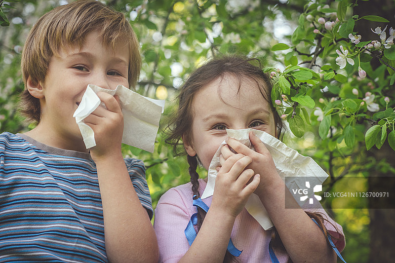 在春季公园里因过敏而清洁鼻子的孩子们图片素材