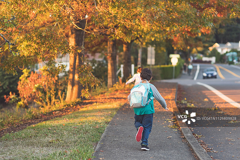小学生背着书包跑向学校图片素材