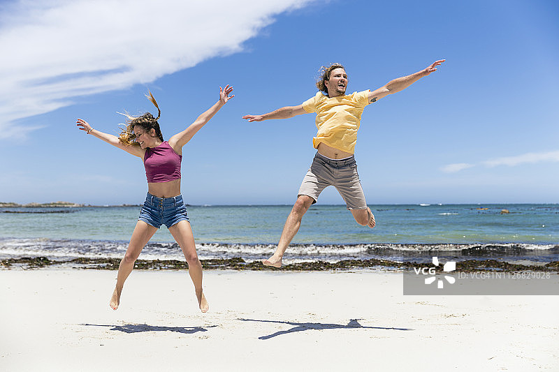 夏季海滩上跳跃玩耍的情侣图片素材
