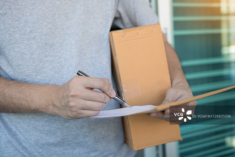 房屋前，顾客使用笔在收据上签字的特写镜头图片素材