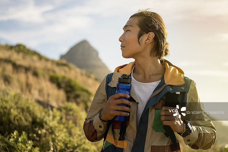 沉思的徒步旅行者站在山丘上面对天空图片素材