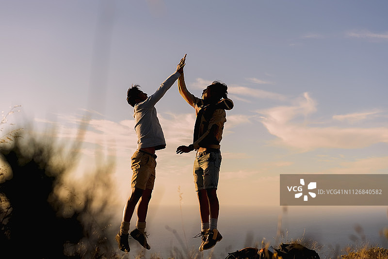 快乐的登山者在山上海边击掌图片素材