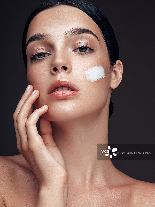美丽年轻的女人涂抹护肤霜图片素材