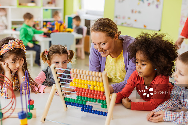 快乐的老师在幼儿园教孩子们用算盘数数图片素材