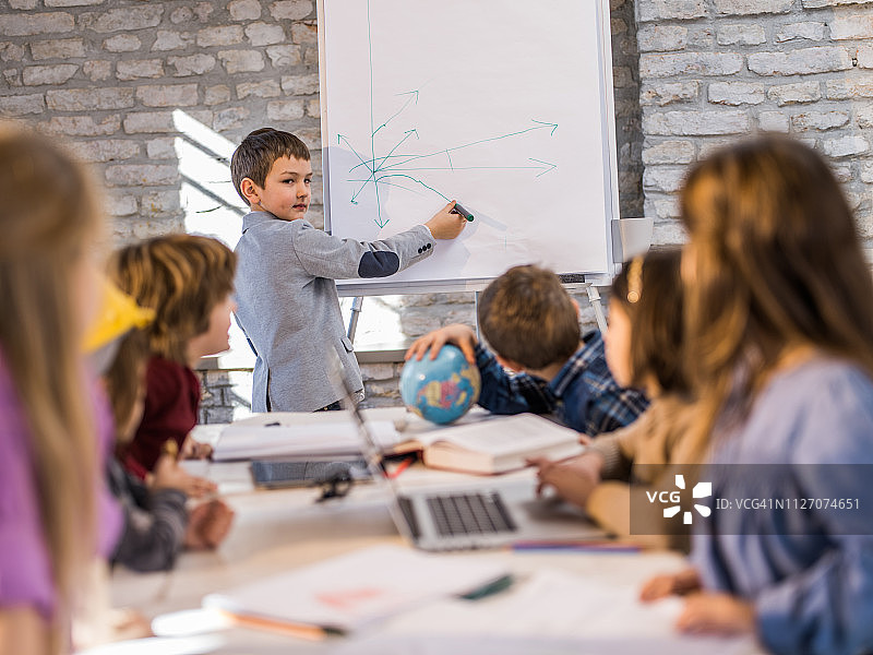 在办公室向朋友们做展示的小企业男孩图片素材