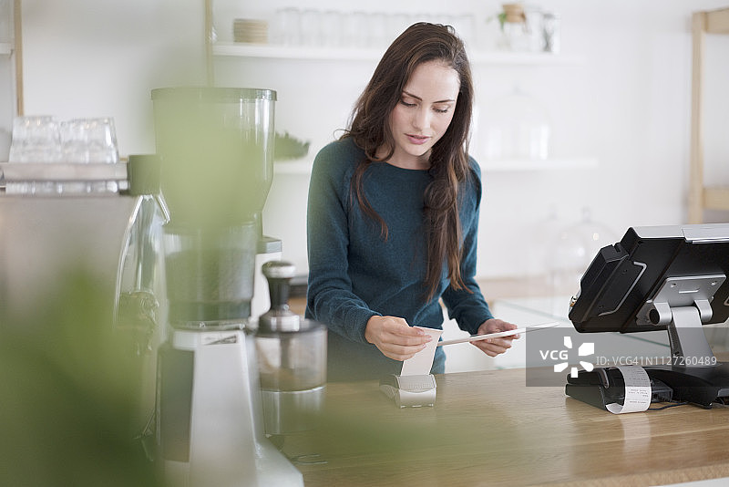 咖啡师在咖啡馆手持平板电脑和收据图片素材
