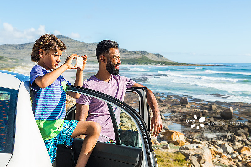 男孩在度假时从车里用智能手机拍照图片素材