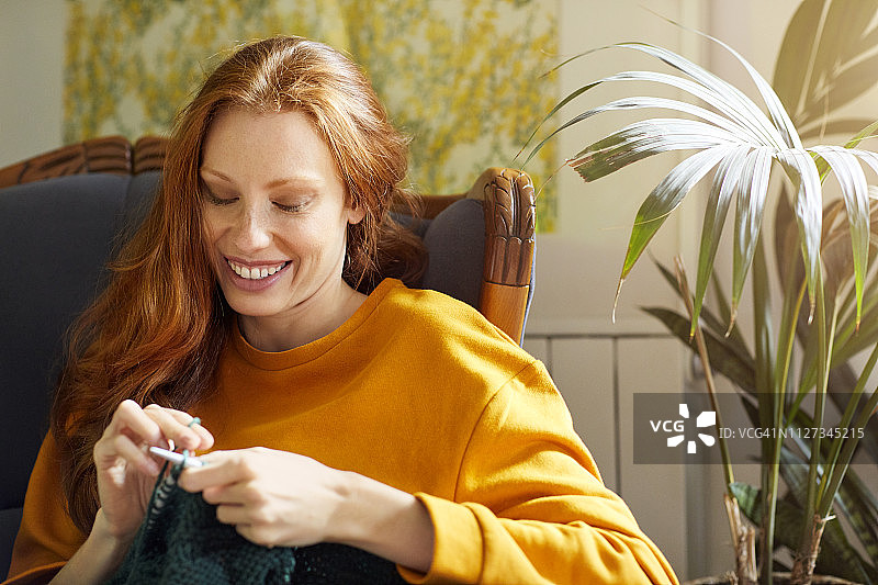 女人坐在椅子上，在植物旁边编织图片素材