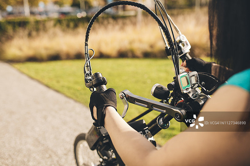 年轻女子在公园里骑运动轮椅。图片素材