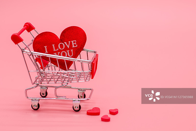粉色背景下购物车里的红心图片素材