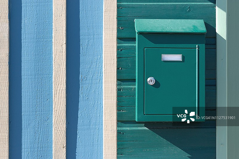 绿松石色邮箱，位于绿松石、白色和浅蓝色木墙上图片素材