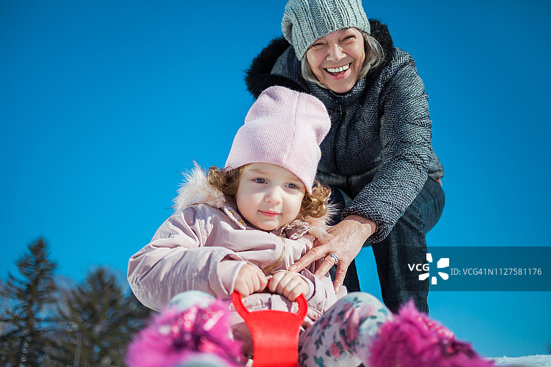 祖母和孙女在雪橇上滑行图片素材