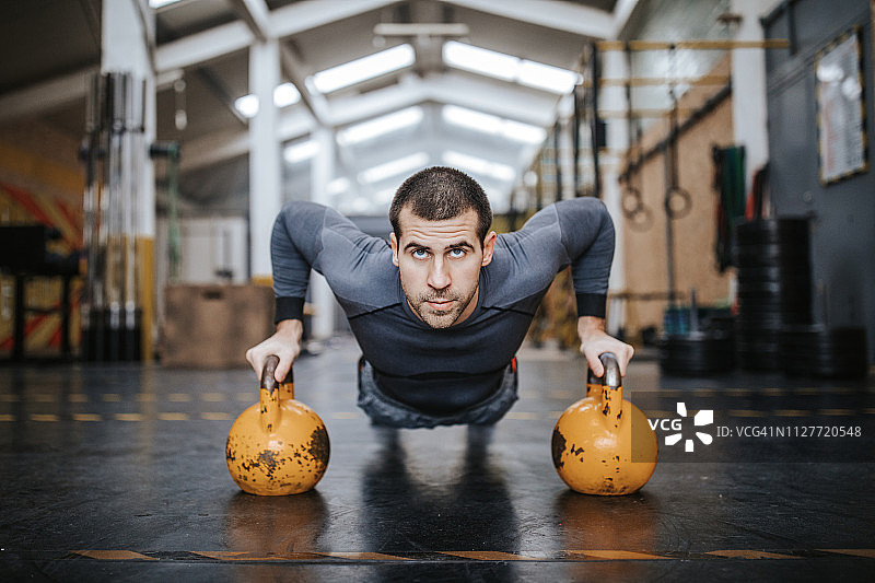 运动员在健身房用壶铃做俯卧撑图片素材