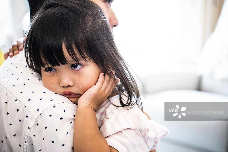 哭泣的中国小女孩，父亲正在安慰她图片素材