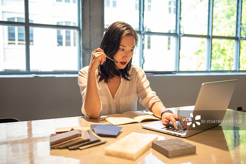 年轻的亚洲女士坐在桌旁图片素材