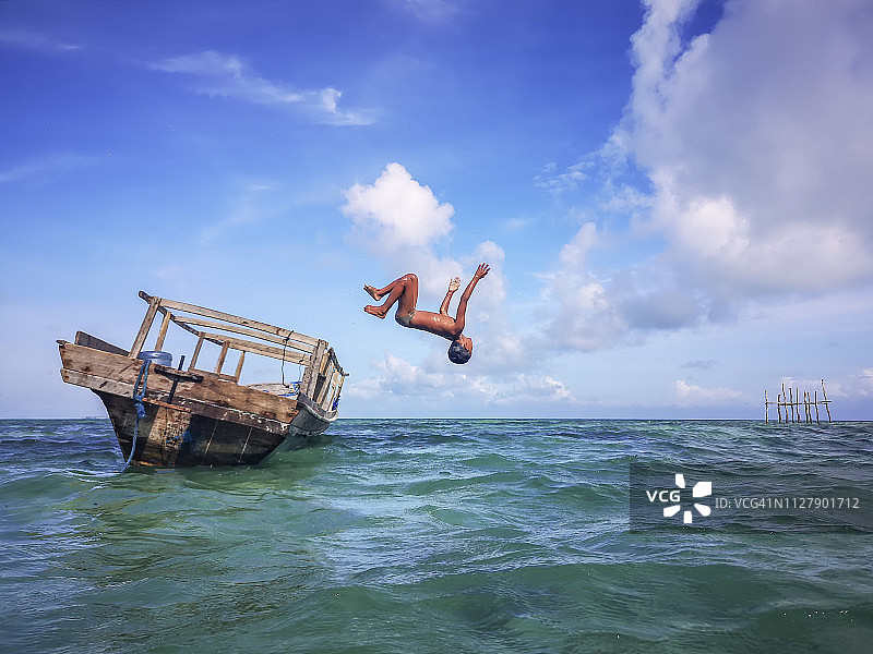 海上吉普赛男孩在旧船上翻筋斗跳水图片素材