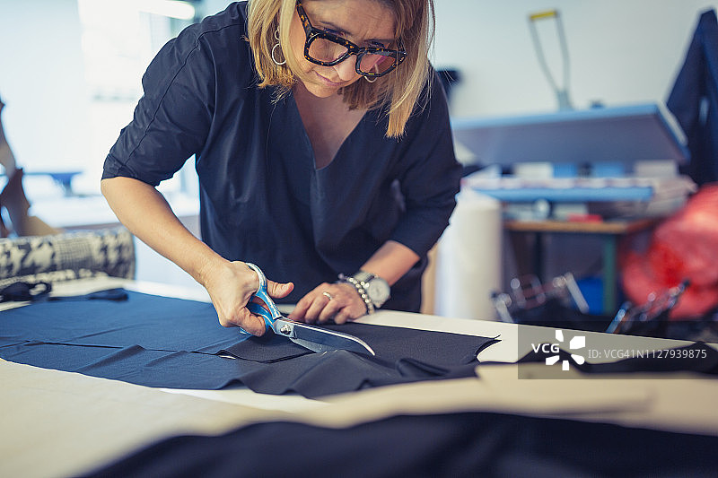 时装设计师用剪刀裁剪纺织品图片素材