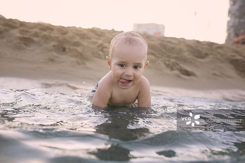 在海滩上吐舌头的男婴图片素材