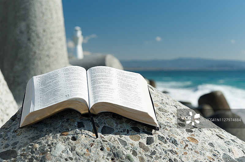 晴朗的一天，蓝色天空下，巨石上摊开的圣经。特写镜头。图片素材
