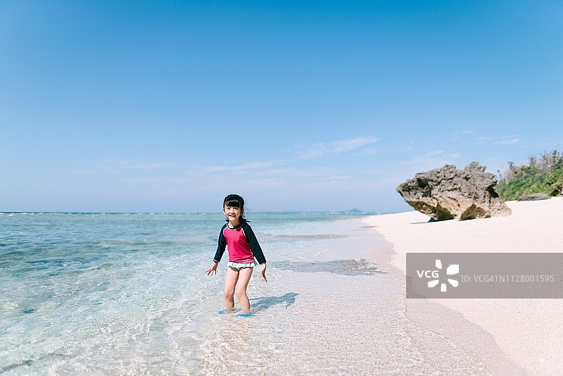 幼儿园女孩在日本白色沙滩的热带浅水中玩耍图片素材