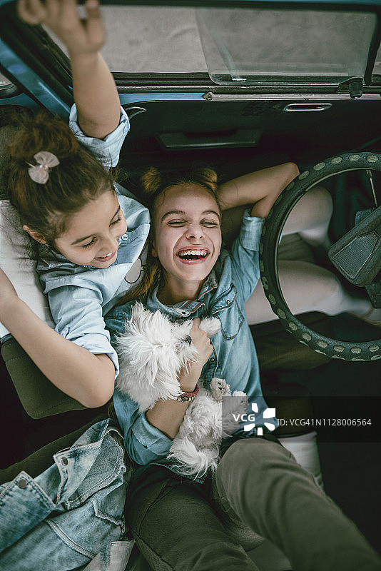 可爱的姐妹和她们的宠物在老爷车里图片素材