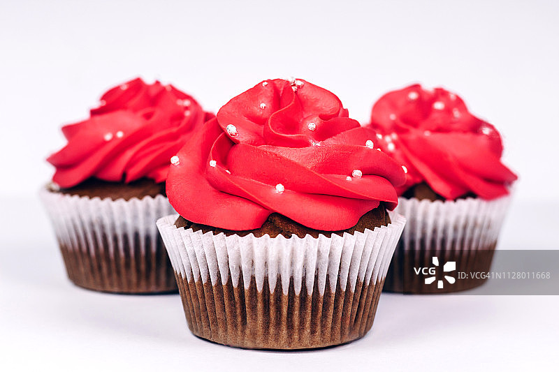 白色背景上鲜红色糖霜的纸杯蛋糕特写图片素材