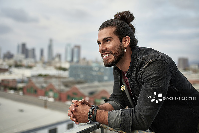 在阳台上双手合十的快乐沉思男人图片素材