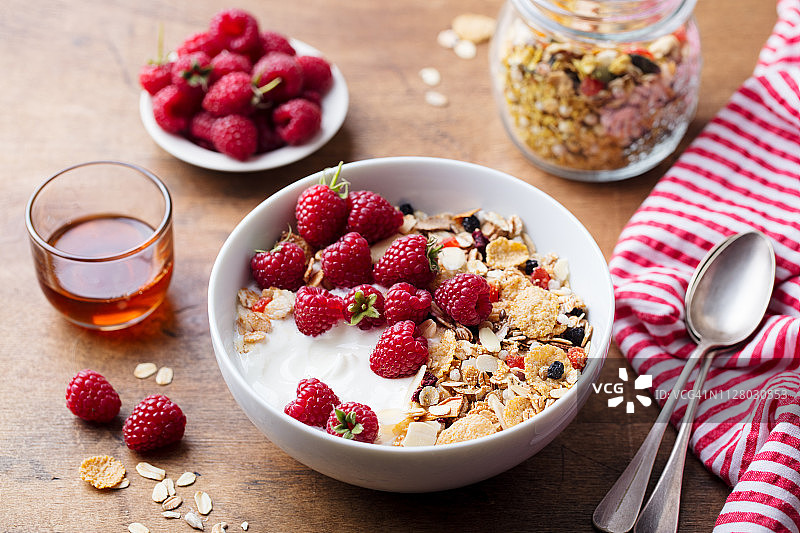 健康的早餐：新鲜的格兰诺拉麦片，搭配酸奶和浆果，木质背景图片素材