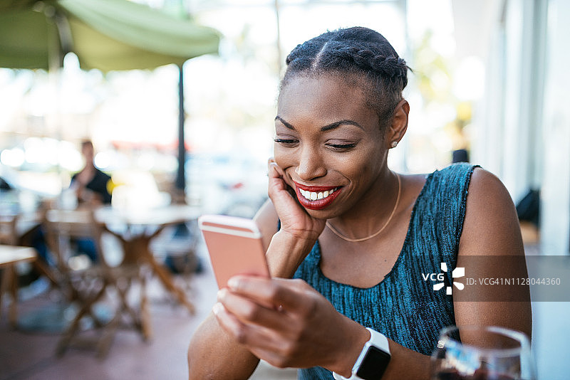 千禧一代西班牙裔女性使用手机在社交媒体上分享内容图片素材