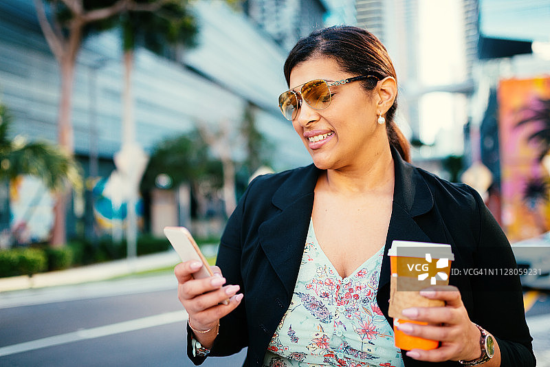 年长的拉丁裔女商人在美国金融区使用智能手机图片素材