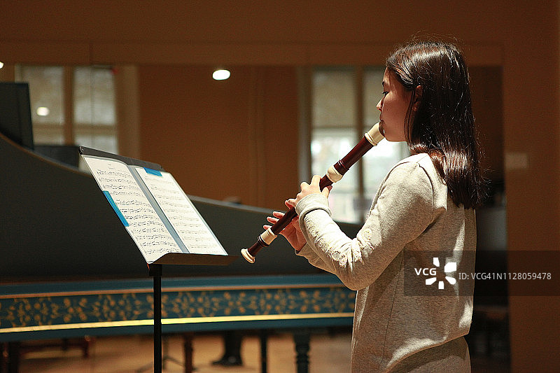 女孩在音乐室吹竖笛的特写图片素材