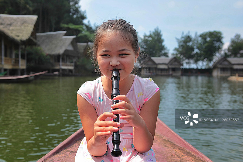 女孩坐在划艇上吹竖笛图片素材